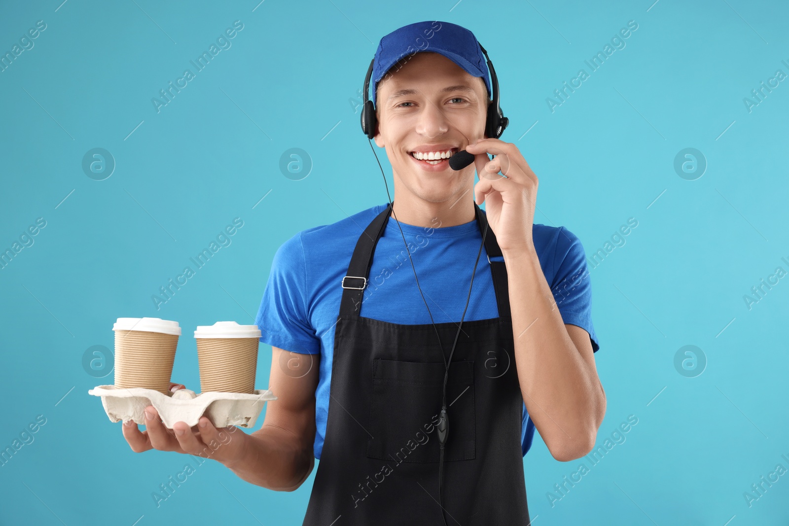 Photo of Fast-food worker with paper cups on light blue background