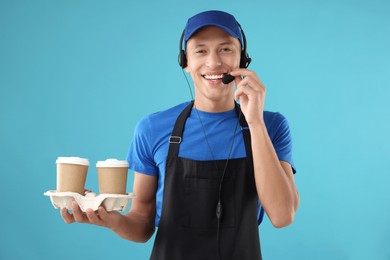 Photo of Fast-food worker with paper cups on light blue background