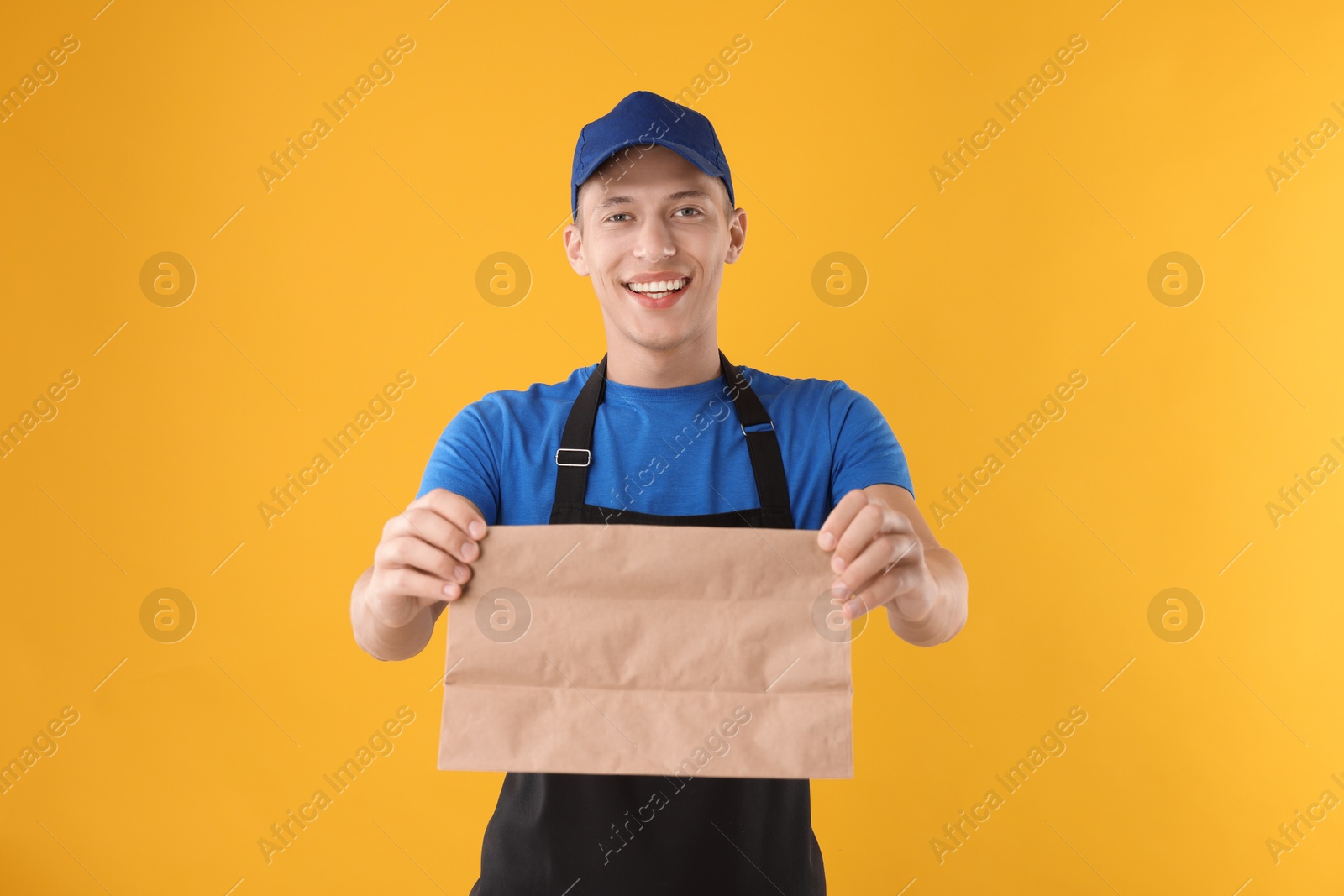 Photo of Fast-food worker with paper bag on orange background