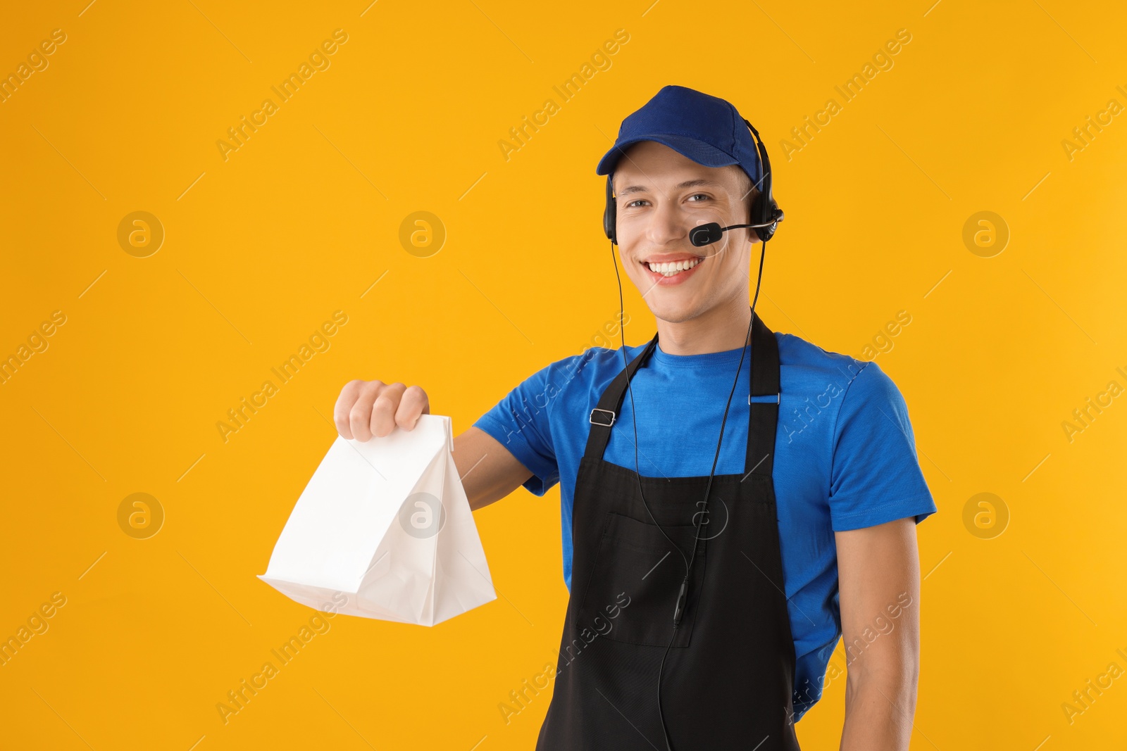 Photo of Fast-food worker with paper bag on orange background