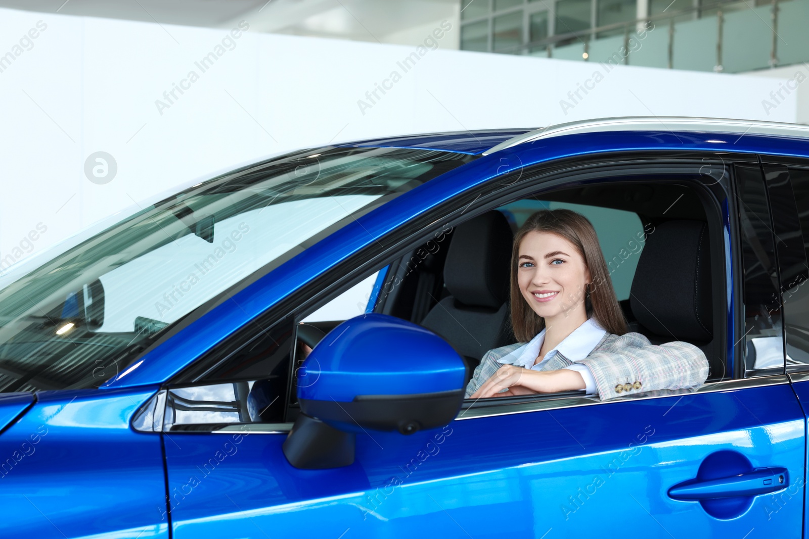 Photo of Young woman inside new blue car in salon