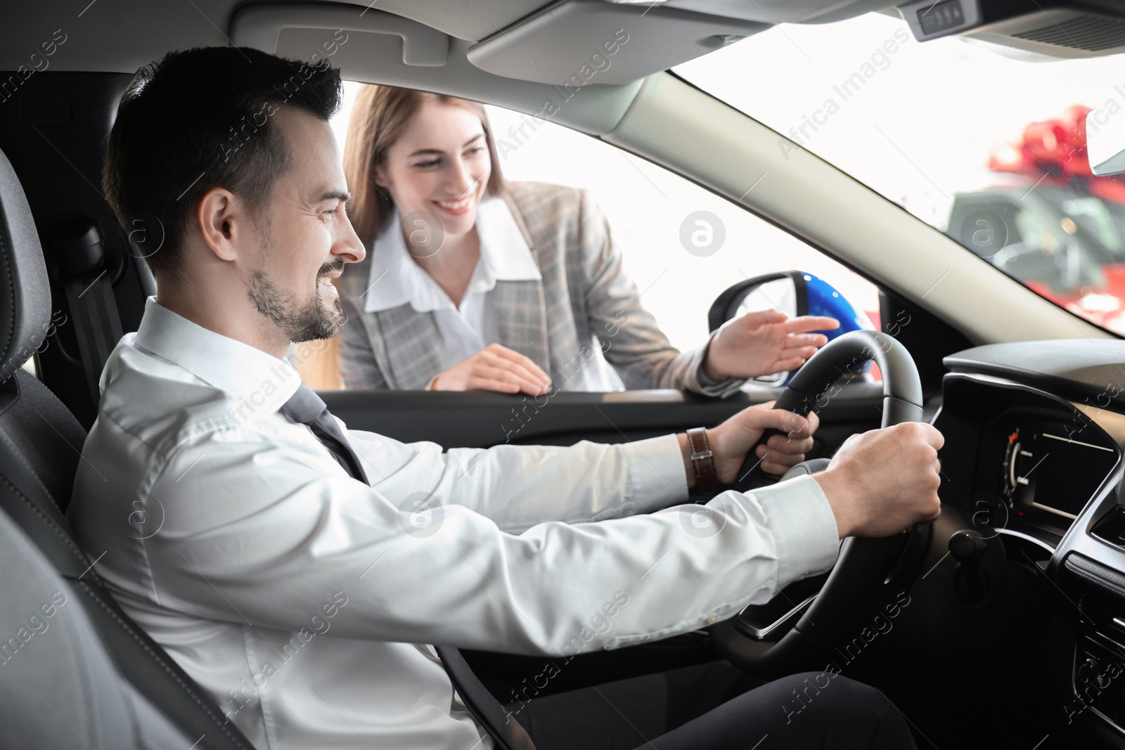 Photo of Saleswoman showing car to client in salon