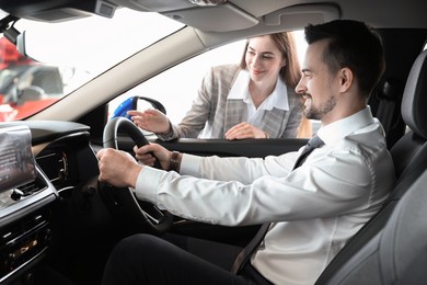 Photo of Saleswoman showing car to client in salon