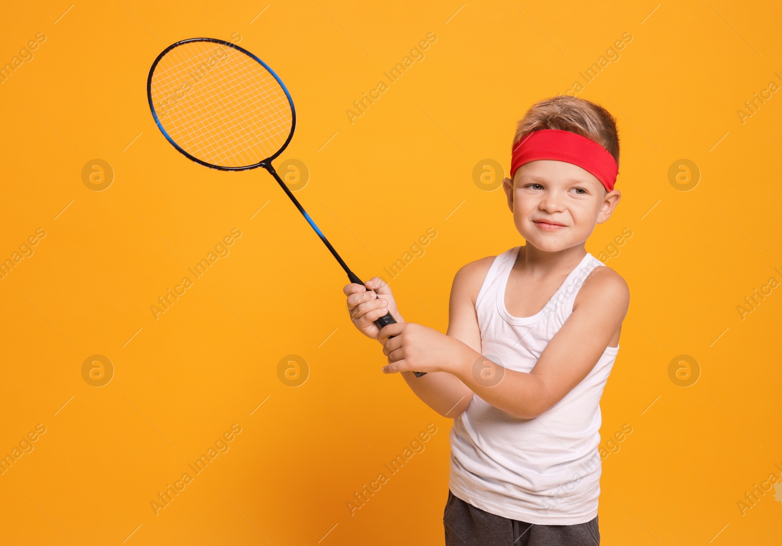 Photo of Little boy with badminton racket on orange background