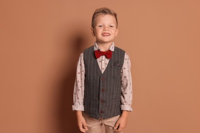 Photo of Portrait of little boy with stylish clothes on brown background, space for text