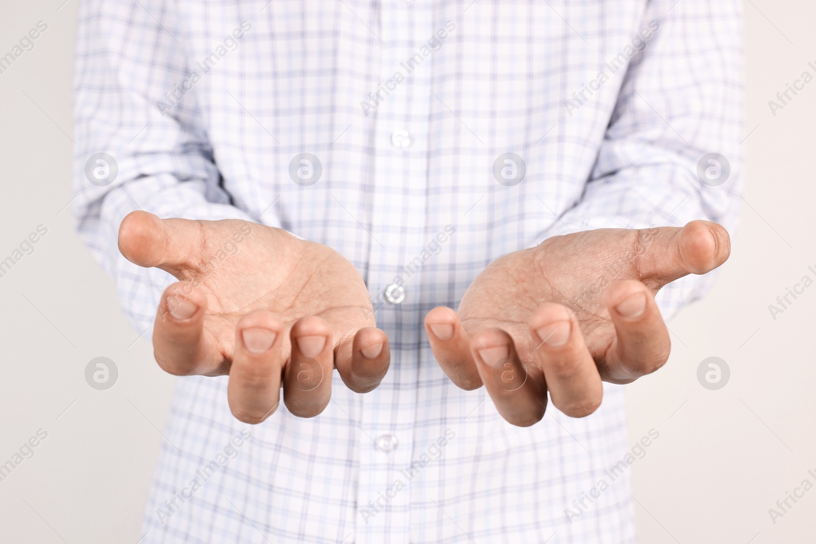 Photo of Man holding something on light grey background, closeup