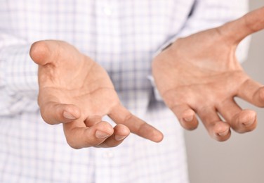 Photo of Man holding something on grey background, closeup