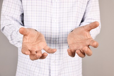 Photo of Man holding something on grey background, closeup