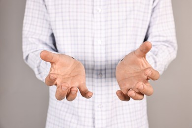 Photo of Man holding something on grey background, closeup