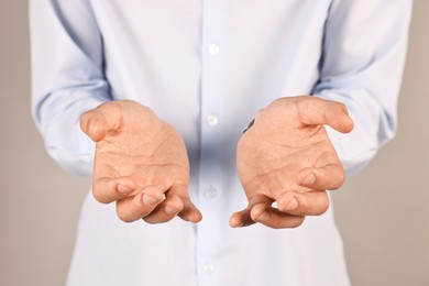 Photo of Man holding something on grey background, closeup