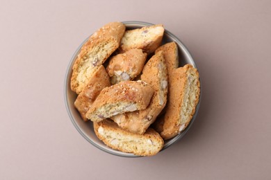 Photo of Tasty almond biscuits (Cantuccini) in bowl on beige background, top view