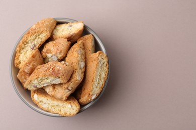 Photo of Tasty almond biscuits (Cantuccini) in bowl on beige background, top view. Space for text