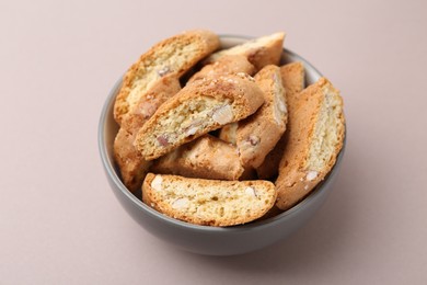 Photo of Tasty almond biscuits (Cantuccini) in bowl on beige background, closeup