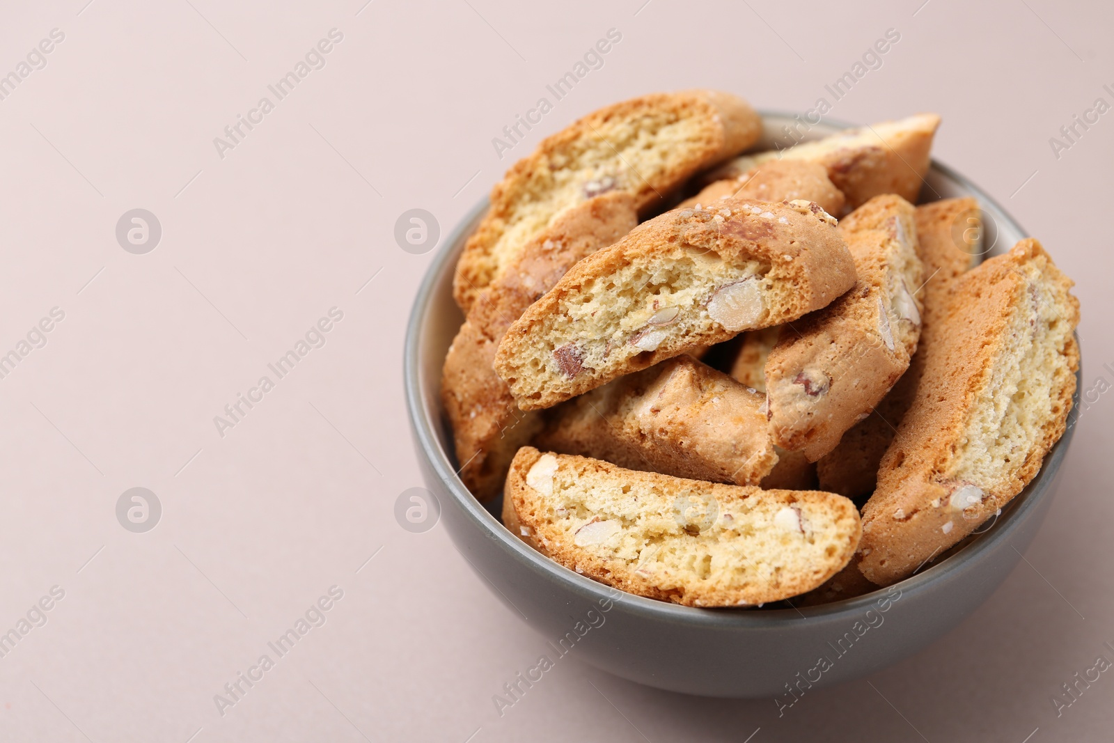 Photo of Tasty almond biscuits (Cantuccini) in bowl on beige background, closeup. Space for text