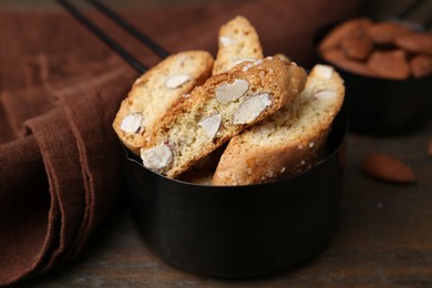 Photo of Tasty almond biscuits (Cantuccini) in scoop on wooden table, closeup