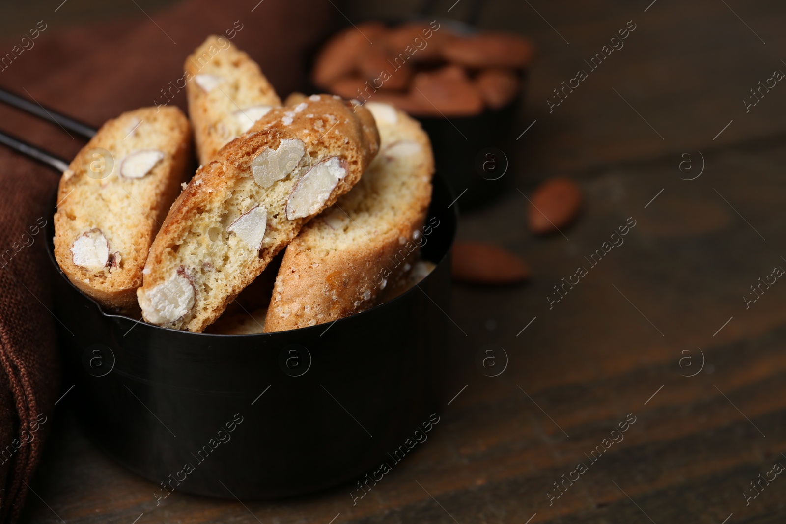 Photo of Tasty almond biscuits (Cantuccini) in scoop on wooden table, closeup. Space for text