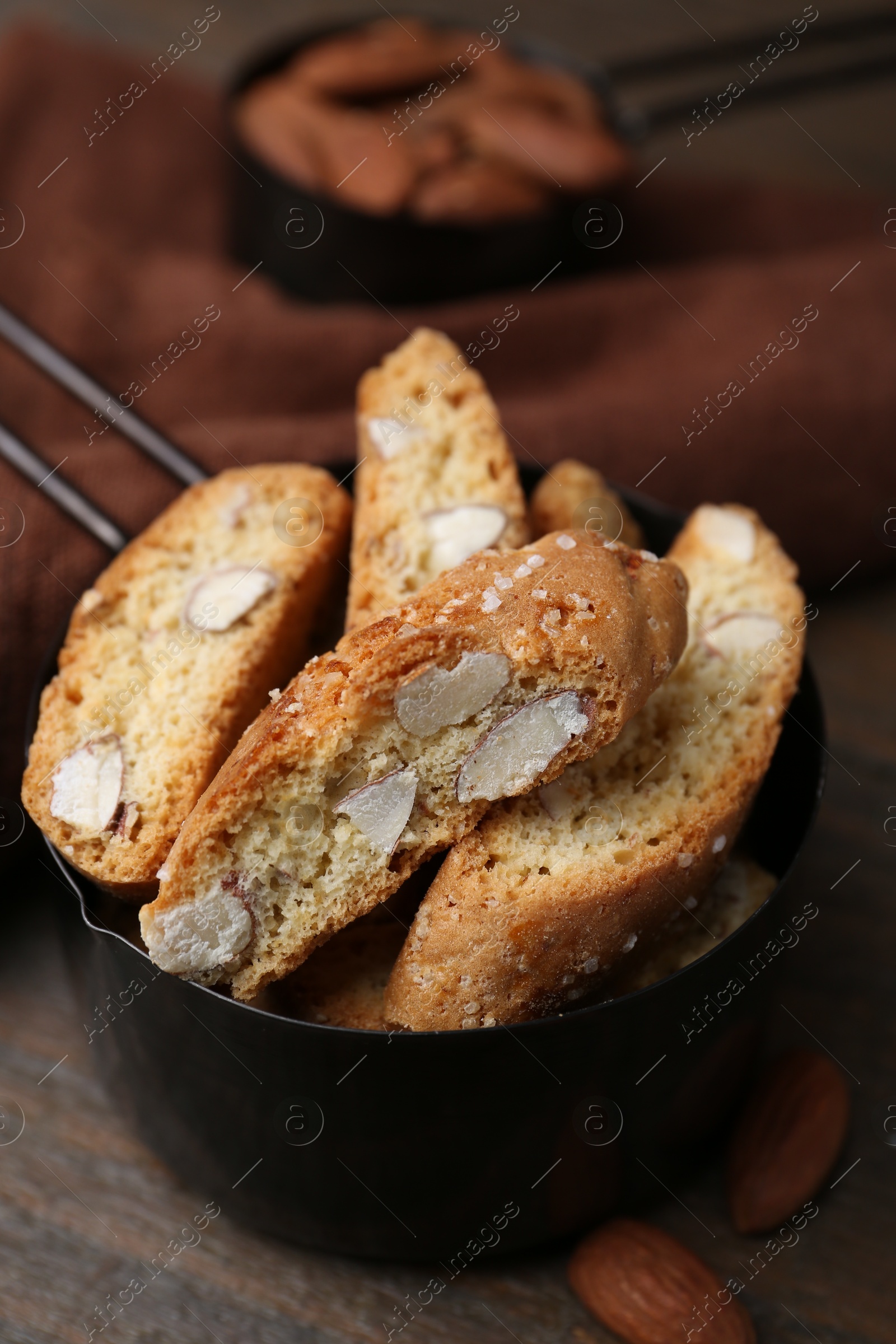 Photo of Tasty almond biscuits (Cantuccini) in scoop and nuts on wooden table, closeup