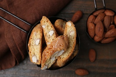 Photo of Tasty almond biscuits (Cantuccini) in scoop and nuts on wooden table, flat lay