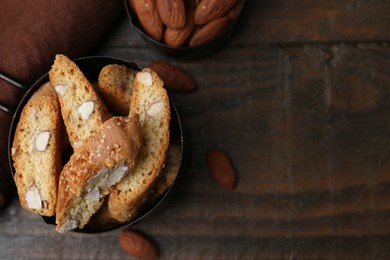 Photo of Tasty almond biscuits (Cantuccini) in scoop and nuts on wooden table, flat lay. Space for text