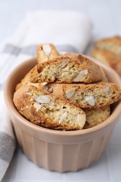 Photo of Tasty almond biscuits (Cantuccini) in bowl on white tiled table, closeup