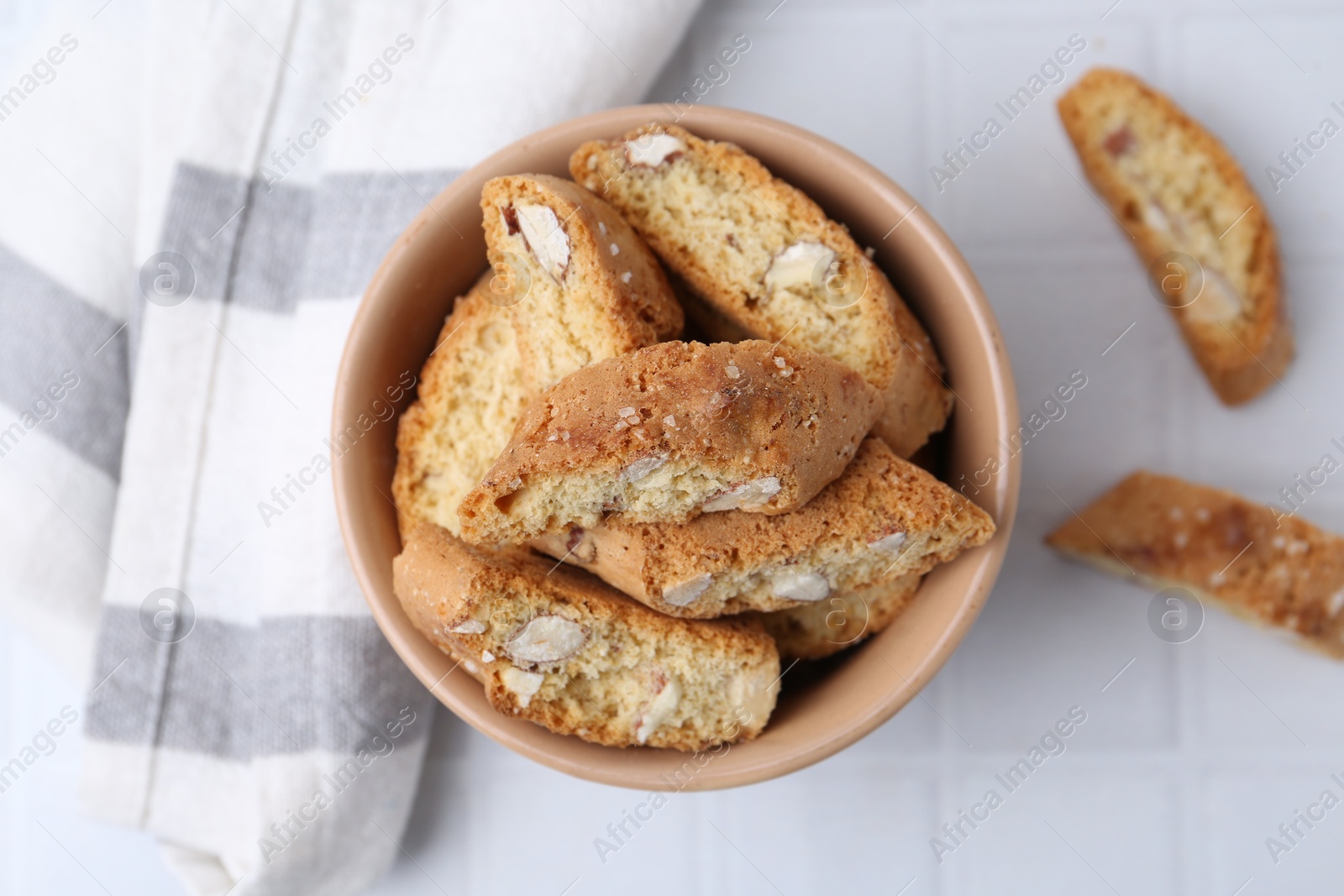 Photo of Tasty almond biscuits (Cantuccini) on white tiled table, flat lay