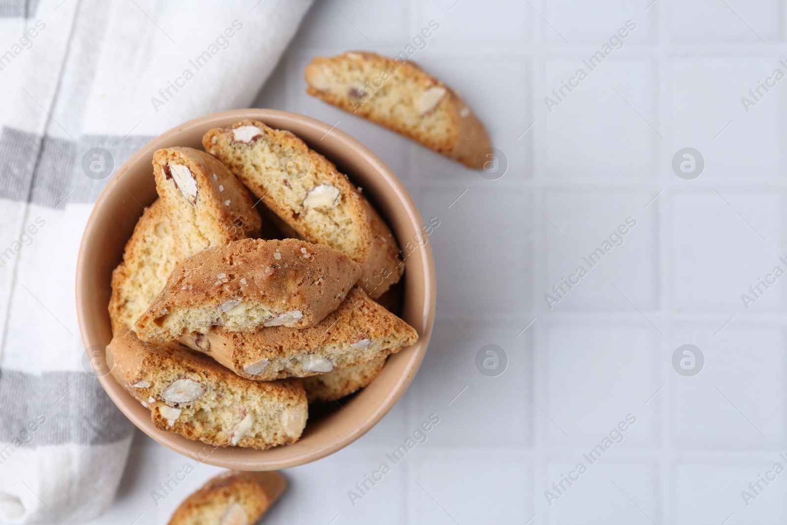 Photo of Tasty almond biscuits (Cantuccini) on white tiled table, flat lay. Space for text