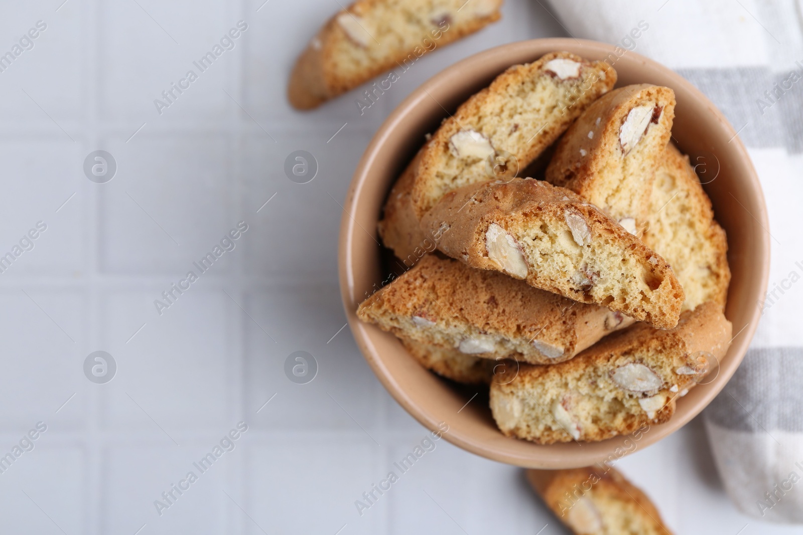 Photo of Tasty almond biscuits (Cantuccini) on white tiled table, flat lay. Space for text