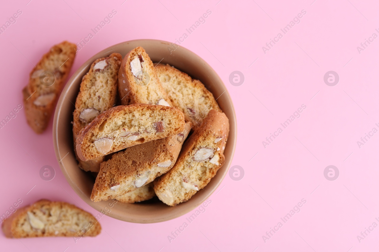 Photo of Tasty almond biscuits (Cantuccini) on pink background, flat lay. Space for text