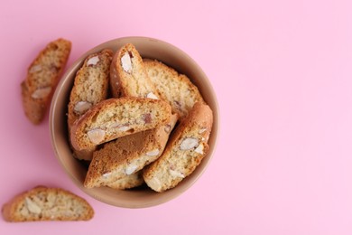 Photo of Tasty almond biscuits (Cantuccini) on pink background, flat lay. Space for text