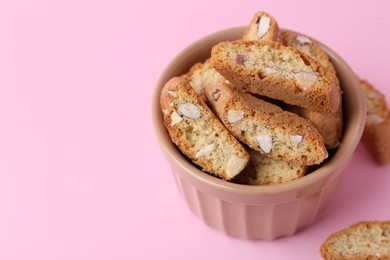 Photo of Tasty almond biscuits (Cantuccini) on pink background, closeup. Space for text