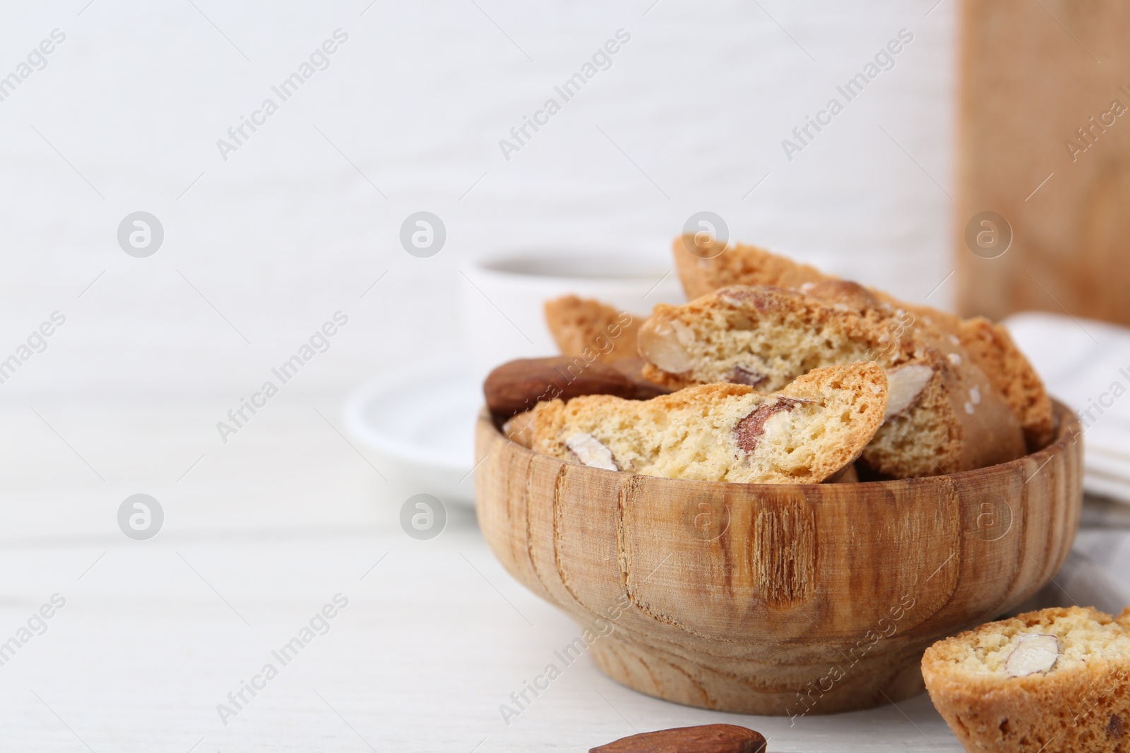 Photo of Tasty almond biscuits (Cantuccini) in bowl on white table, closeup. Space for text