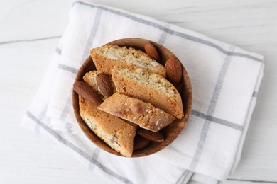 Photo of Tasty almond biscuits (Cantuccini) and nuts in bowl on white wooden table, top view