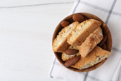 Photo of Tasty almond biscuits (Cantuccini) and nuts in bowl on white table, top view. Space for text