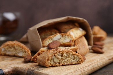 Photo of Tasty almond biscuits (Cantuccini) and nuts on wooden table, closeup