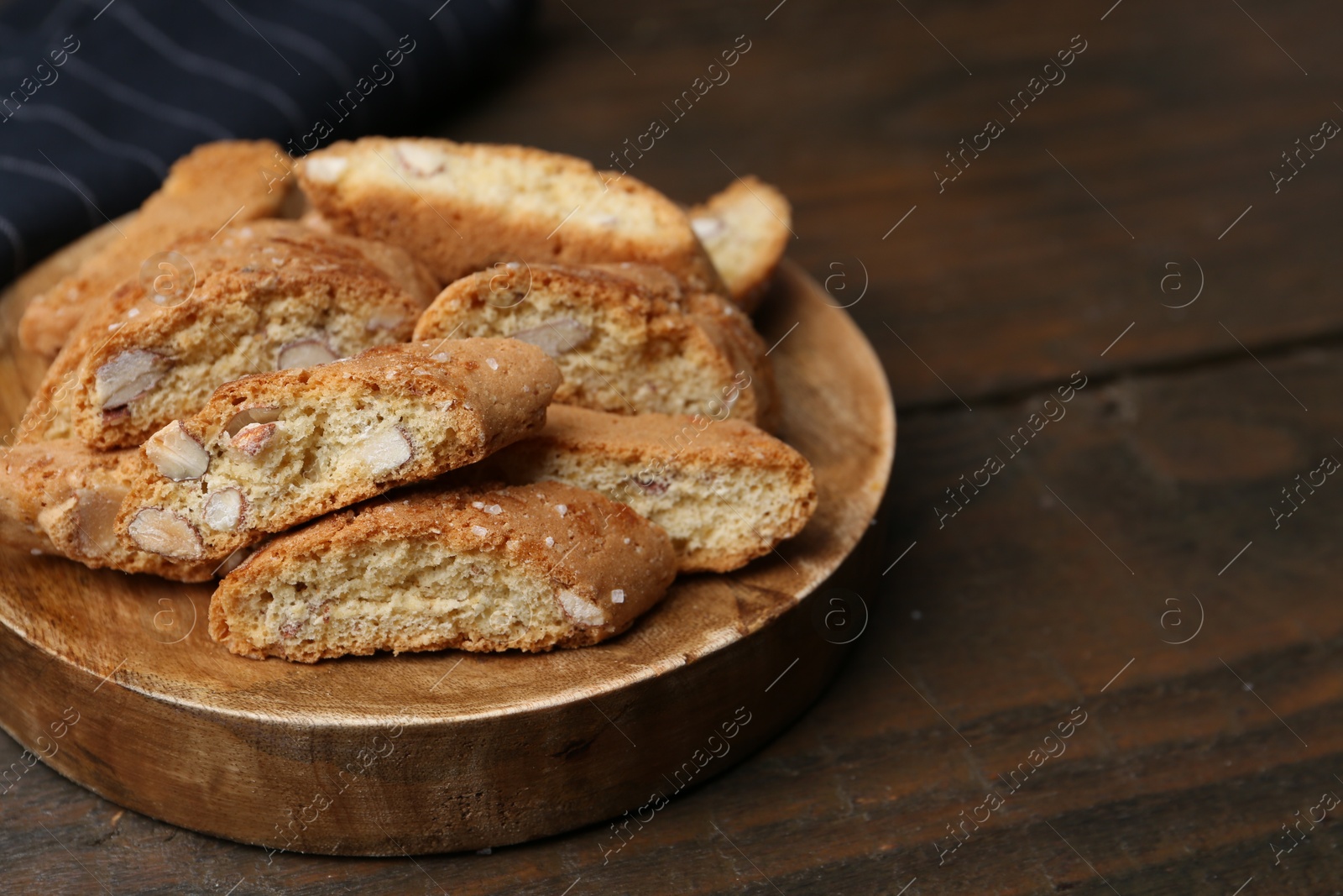 Photo of Tasty almond biscuits (Cantuccini) on wooden table, closeup. Space for text