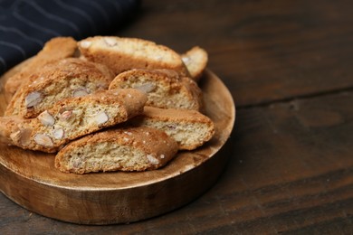 Photo of Tasty almond biscuits (Cantuccini) on wooden table, closeup. Space for text