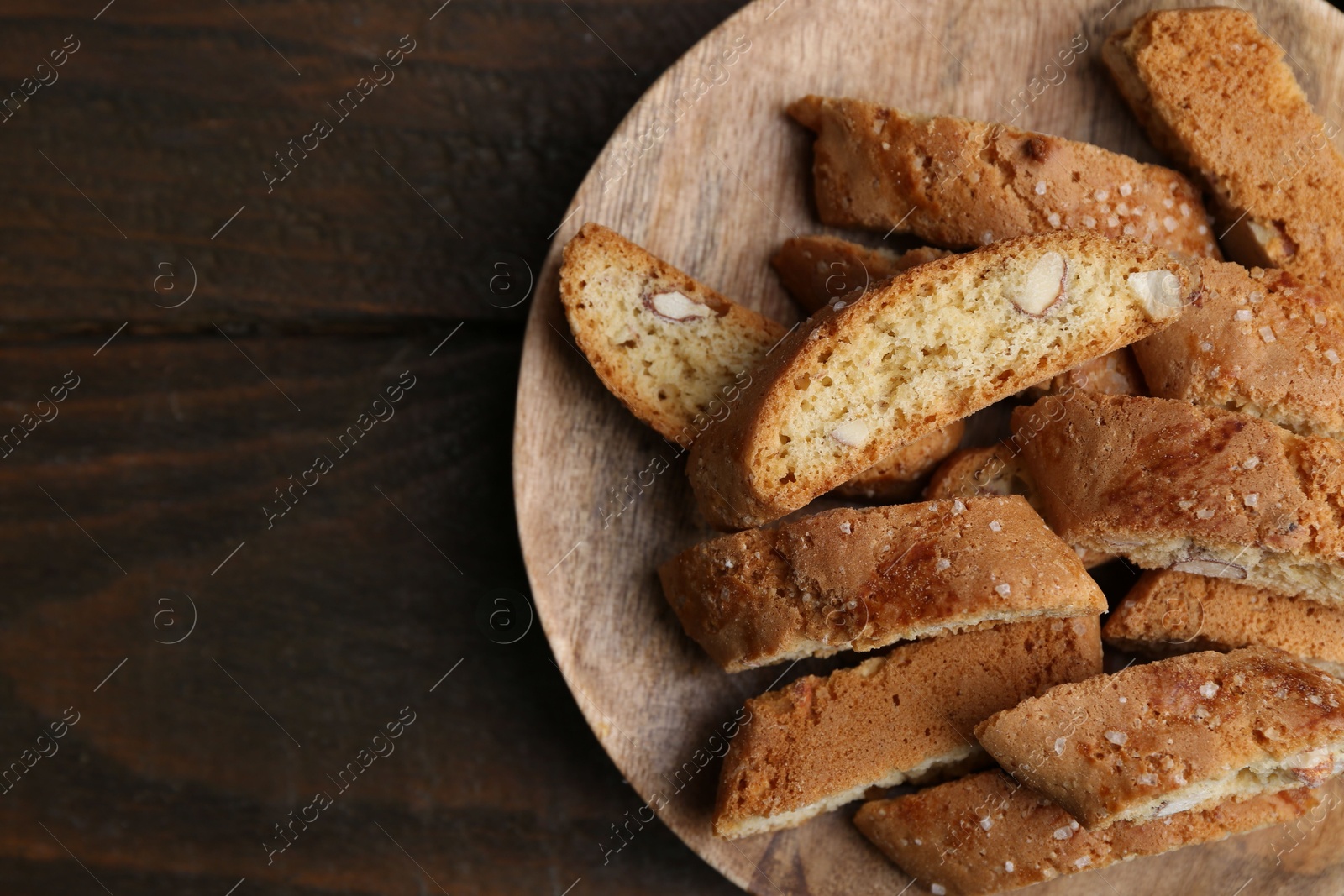 Photo of Tasty almond biscuits (Cantuccini) on wooden table, top view. Space for text