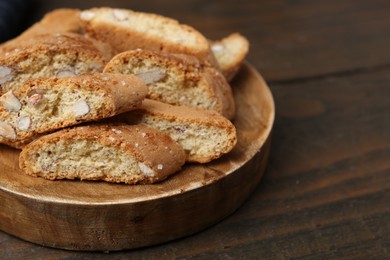 Photo of Tasty almond biscuits (Cantuccini) on wooden table, closeup. Space for text