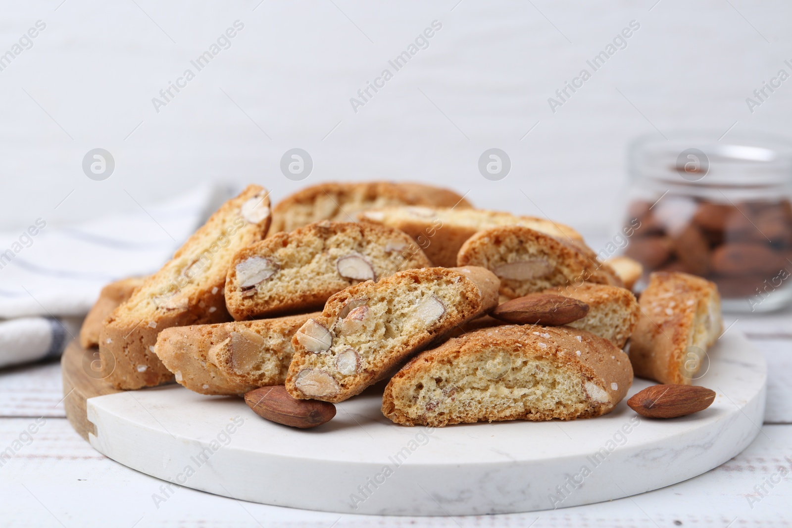 Photo of Tasty almond biscuits (Cantuccini) and nuts on white wooden table, closeup