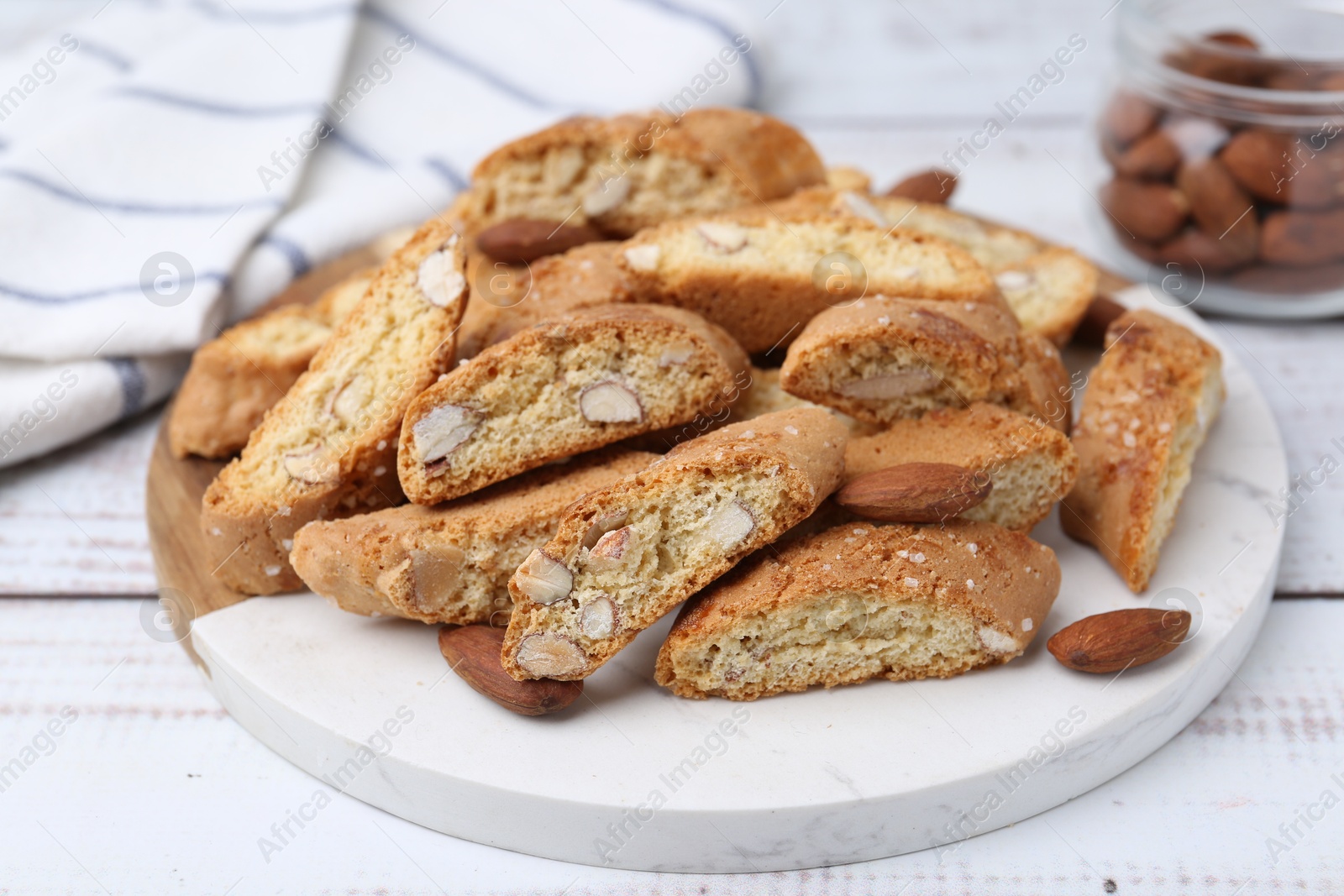 Photo of Tasty almond biscuits (Cantuccini) and nuts on white wooden table, closeup