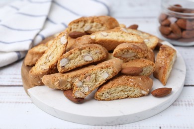 Photo of Tasty almond biscuits (Cantuccini) and nuts on white wooden table, closeup