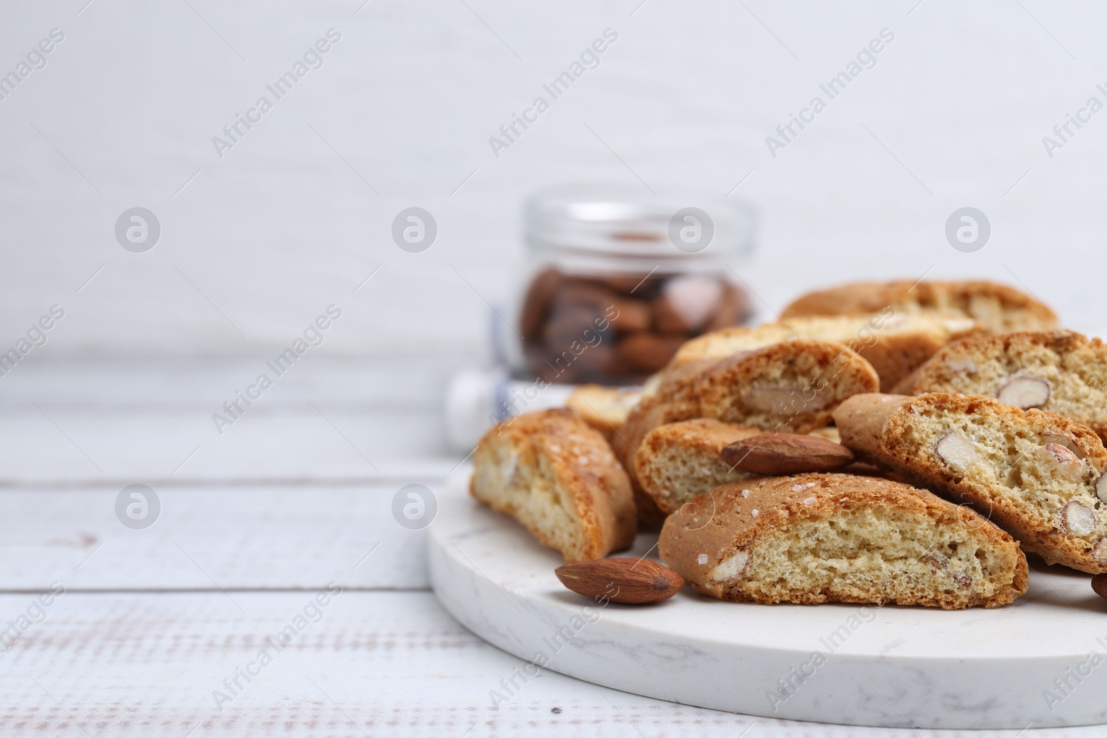 Photo of Tasty almond biscuits (Cantuccini) and nuts on light wooden table, closeup. Space for text