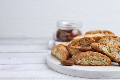 Photo of Tasty almond biscuits (Cantuccini) and nuts on light wooden table, closeup. Space for text