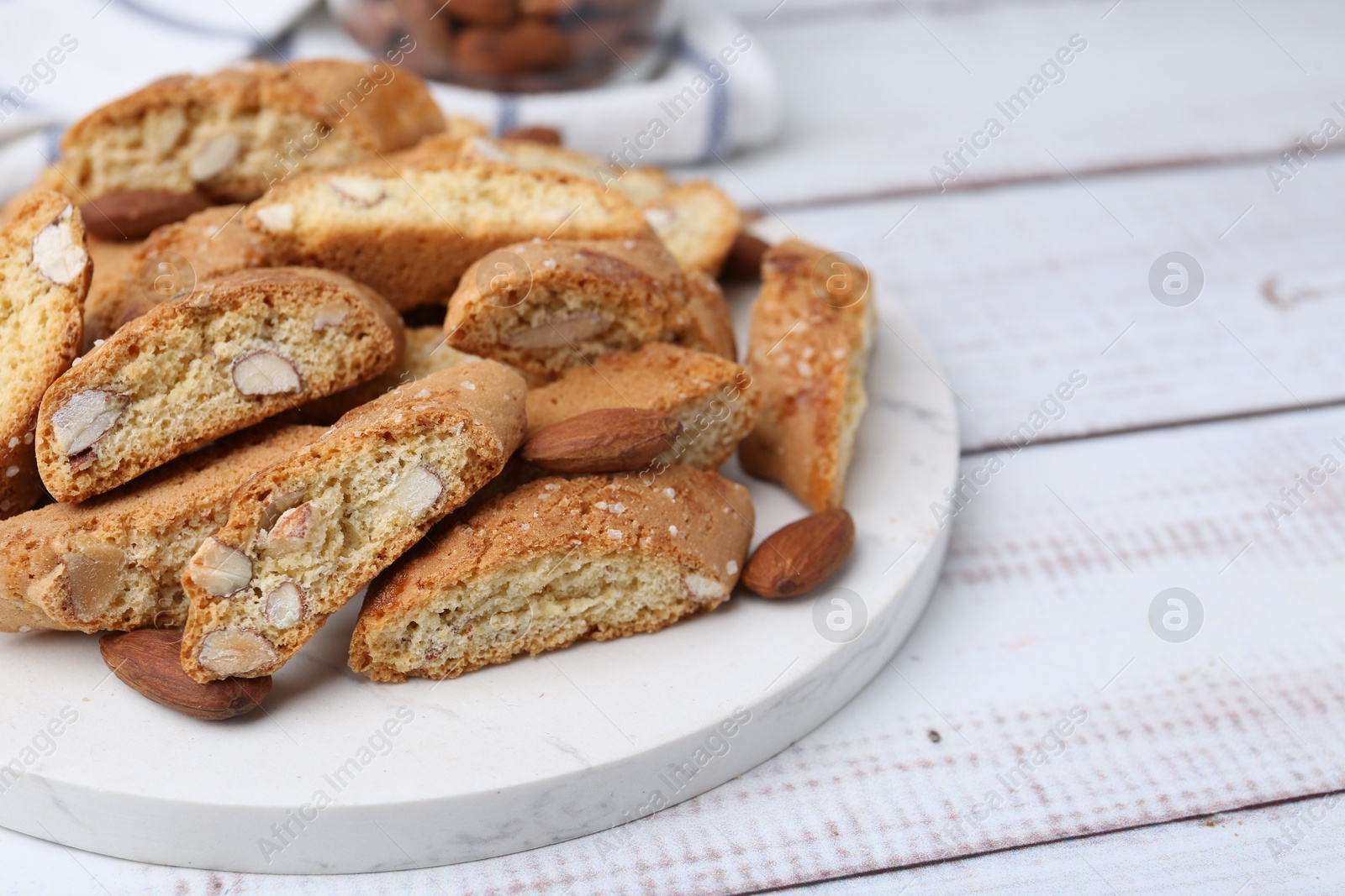 Photo of Tasty almond biscuits (Cantuccini) and nuts on light wooden table, closeup. Space for text