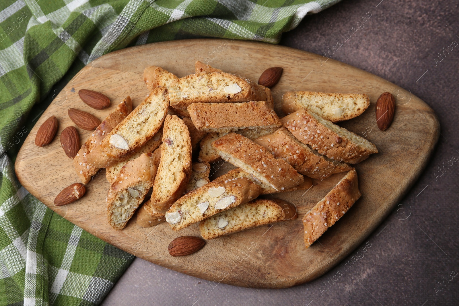 Photo of Tasty almond biscuits (Cantuccini) and nuts on brown textured table, top view