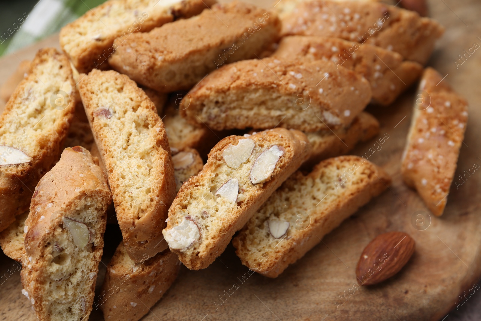 Photo of Tasty almond biscuits (Cantuccini) and nuts on wooden board, closeup