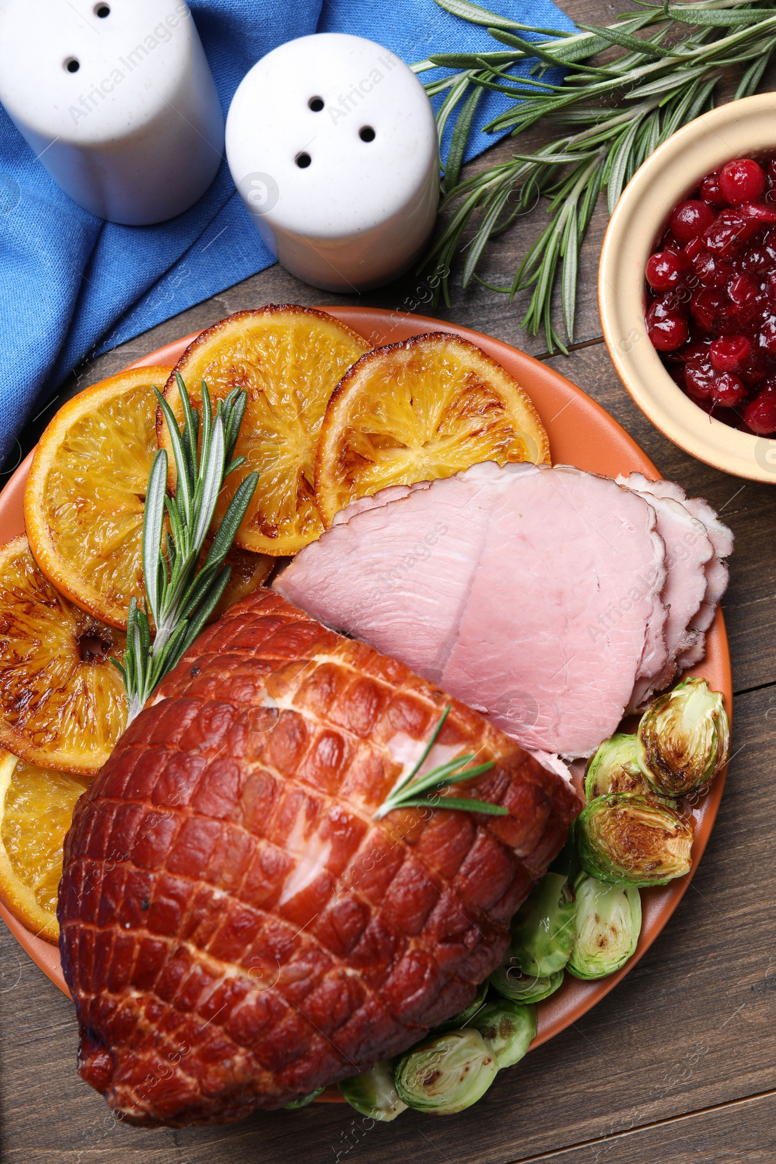 Photo of Christmas food. Tasty baked ham served on wooden table, flat lay