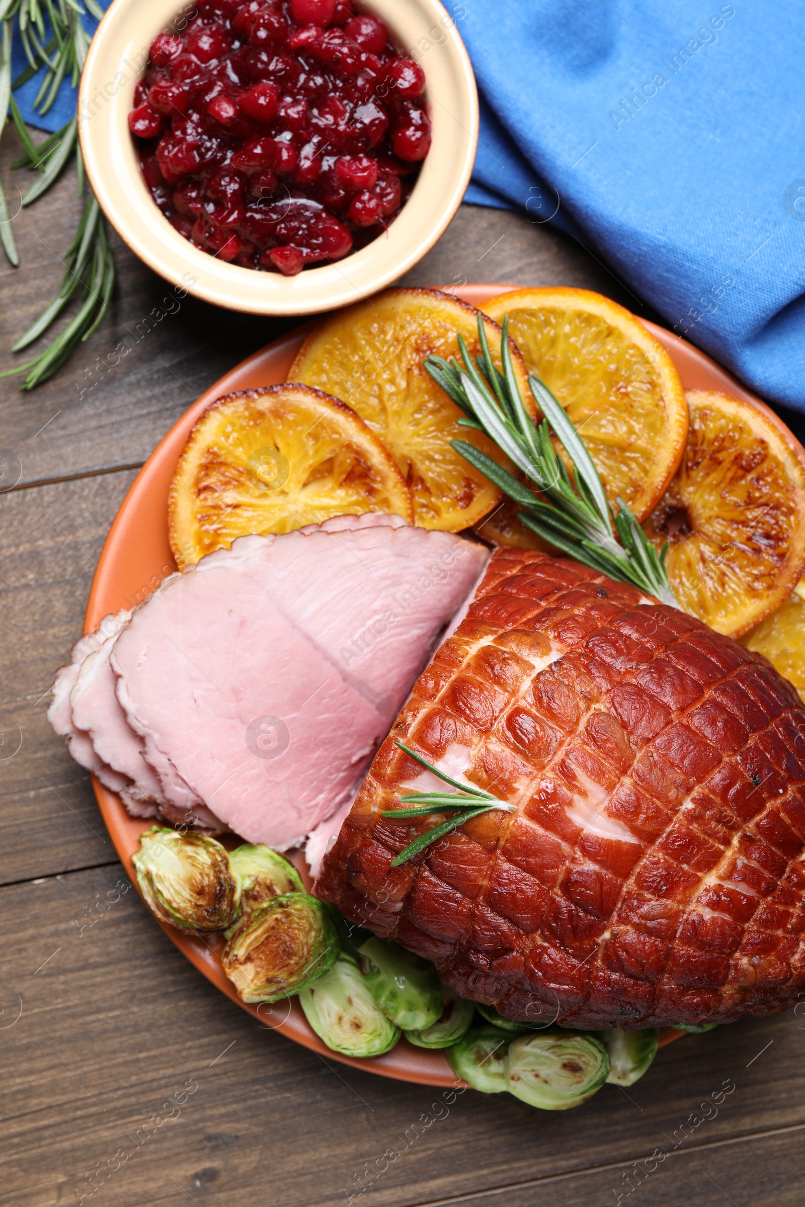 Photo of Christmas food. Tasty baked ham served on wooden table, flat lay