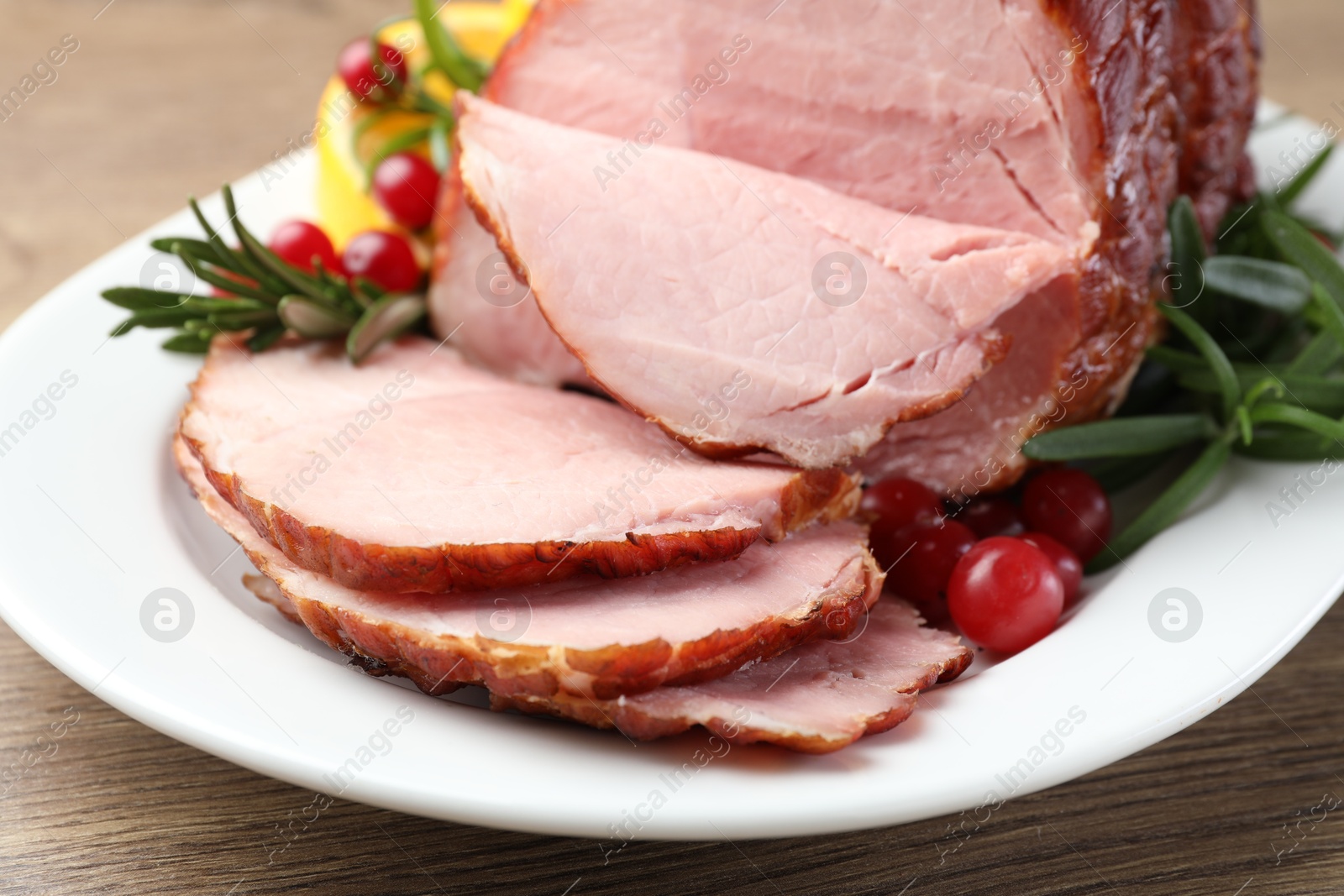 Photo of Christmas food. Tasty baked ham served on wooden table, closeup