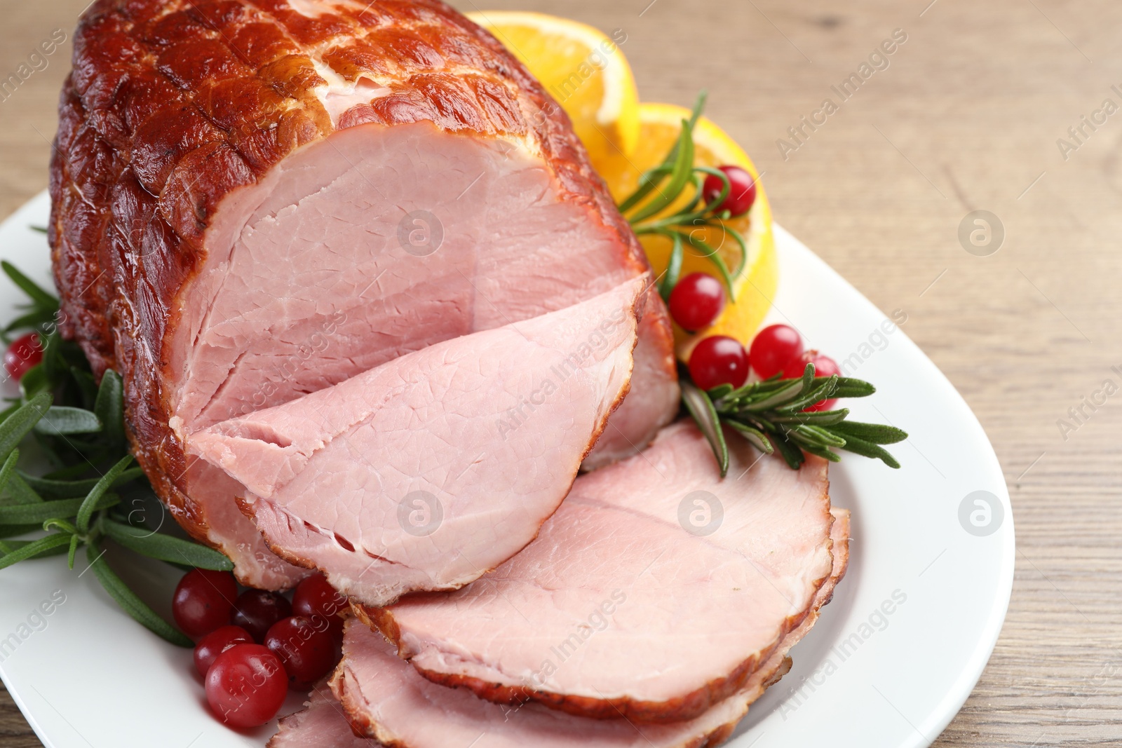 Photo of Christmas food. Tasty baked ham served on wooden table, closeup